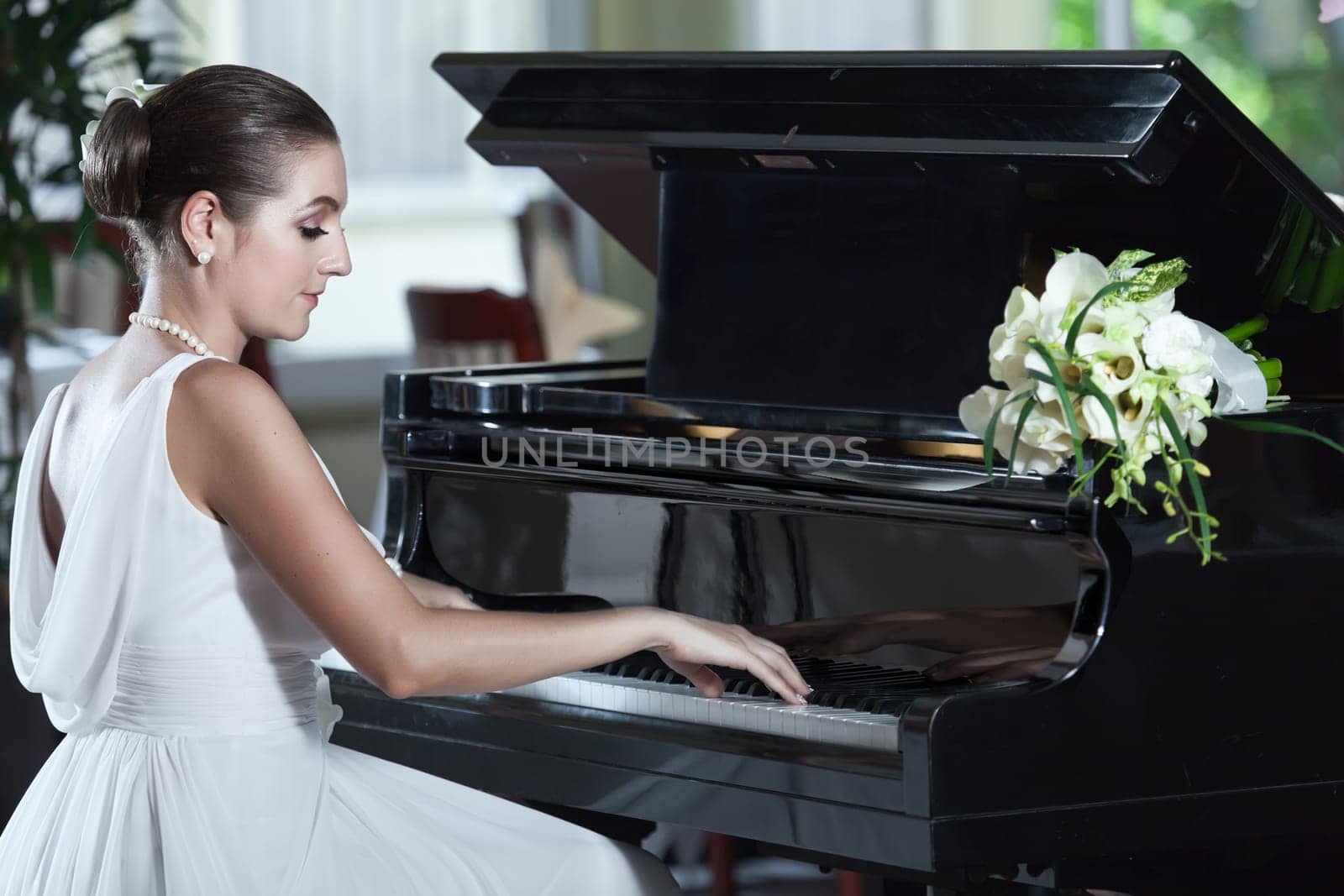 Young beautiful bride playing the grand piano