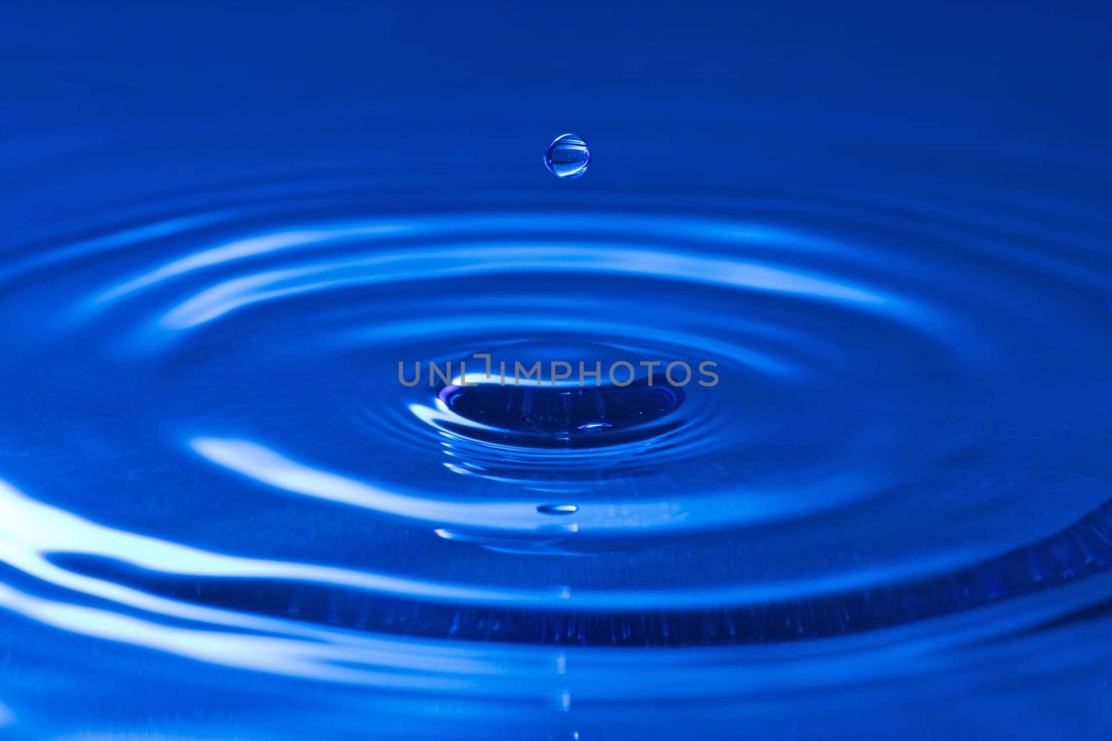 close-up of a droplet, falling in the blue water