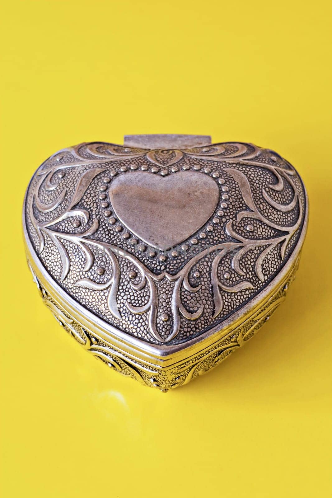 silver ornate heart isolated on yellow background