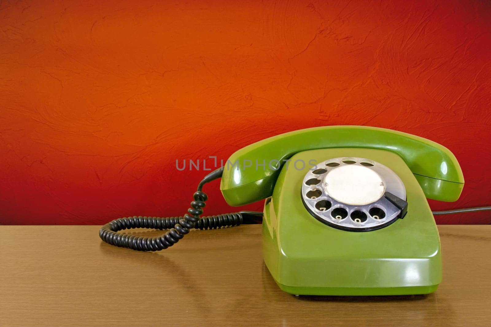 old green scratched phone against red wall background