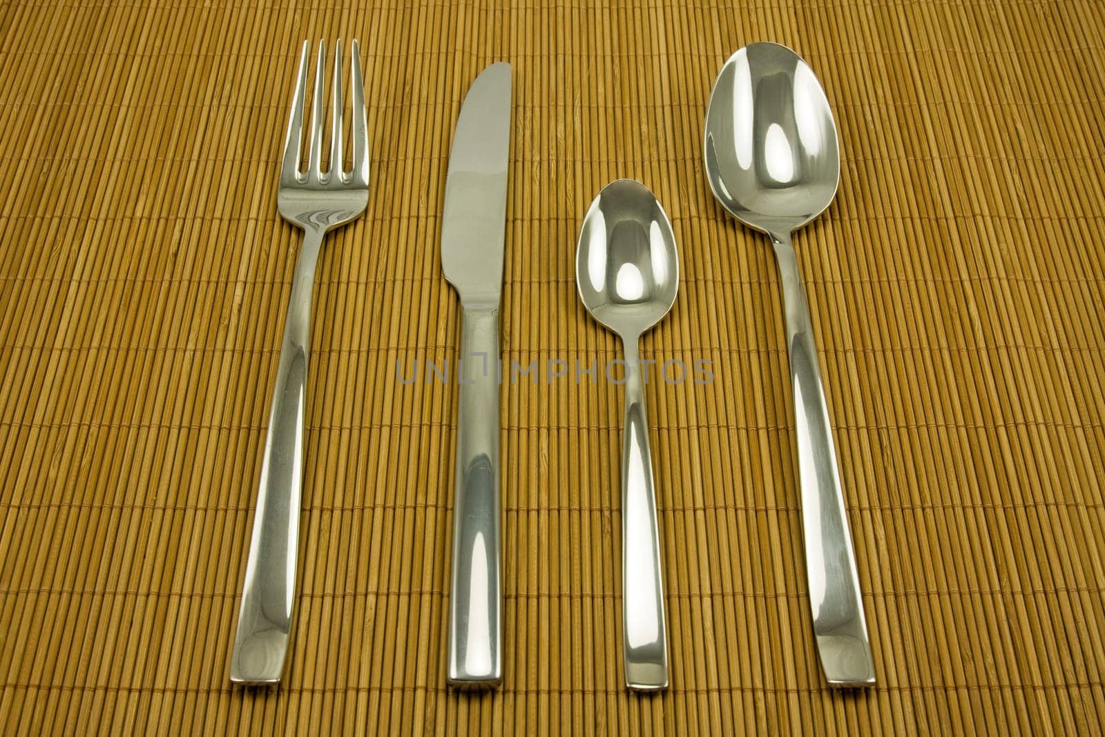 set of stainless steel tableware on bamboo tablecloth