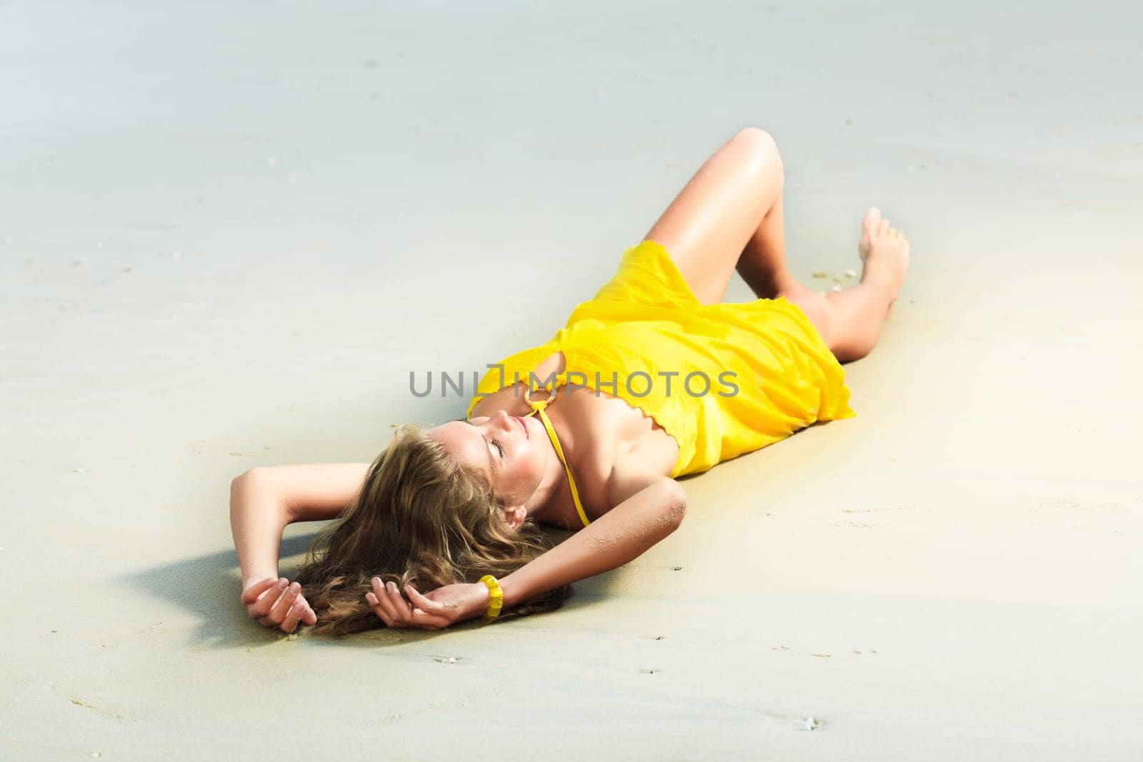 Beautiful woman in yellow dress on the beach