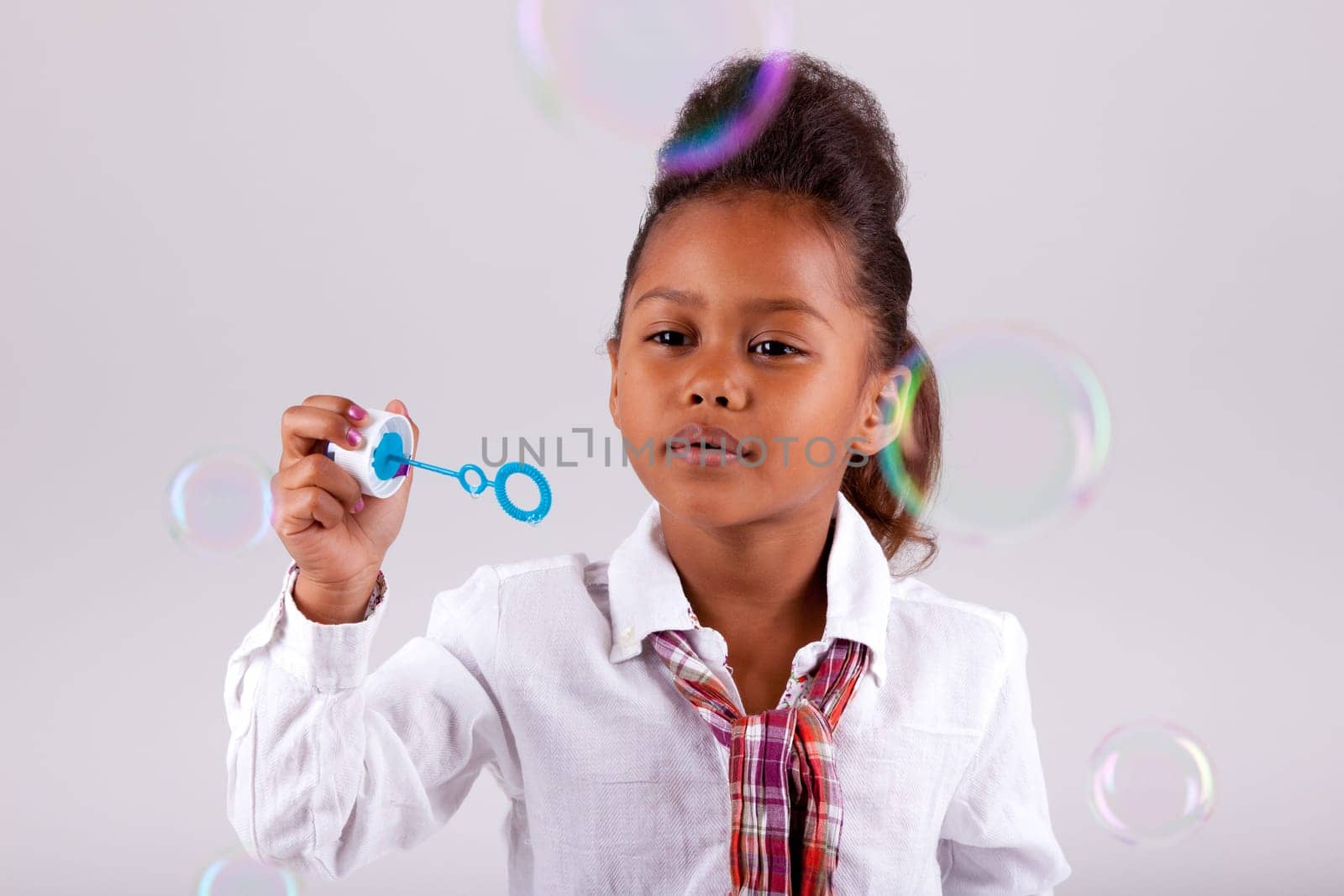 Cute little African American girl blowing soap bubbles