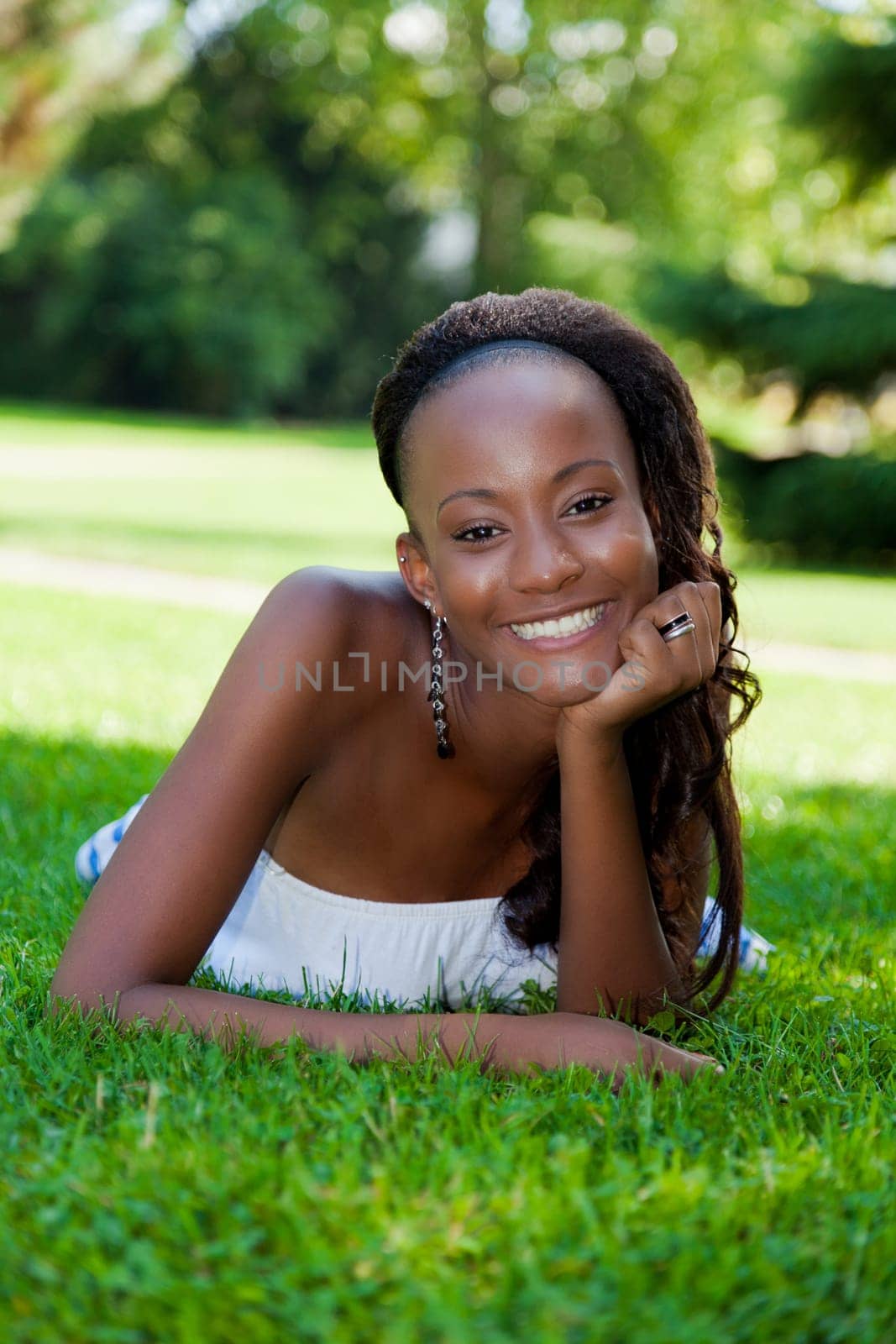 Smiling young african american girl lying down on the grass
