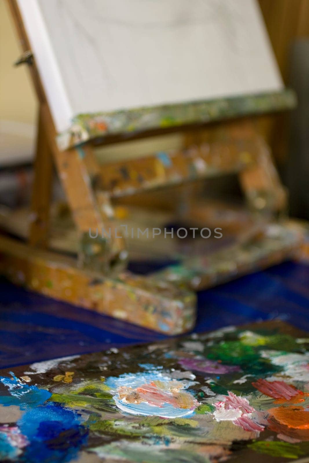 Atelier. Palette with colors, easel in the background