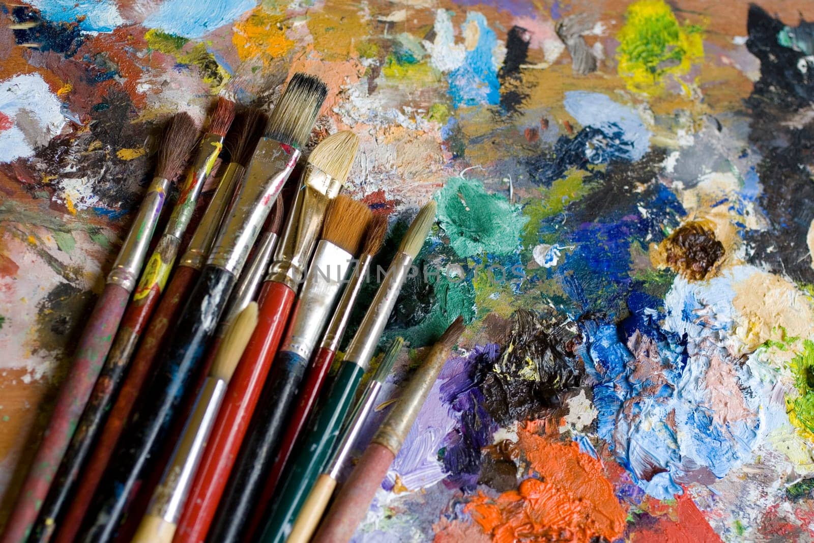 Paintbrushes used and dirty color. Palette on the background
