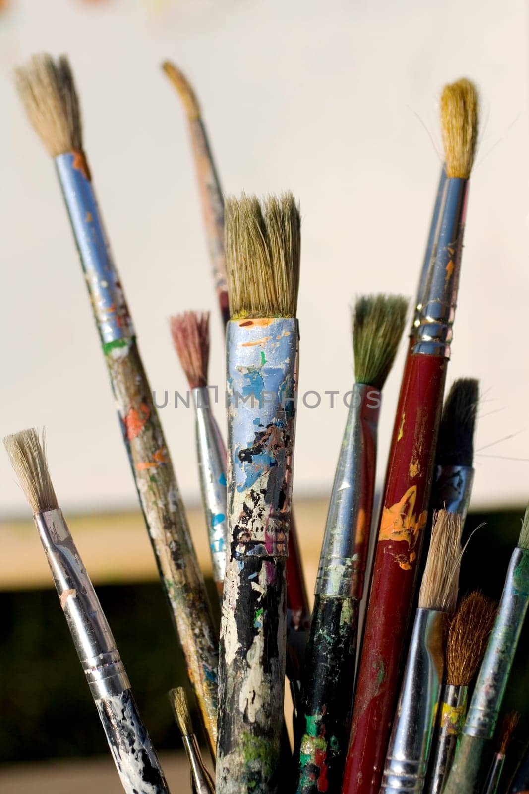 Paintbrushes and painted canvas in the background