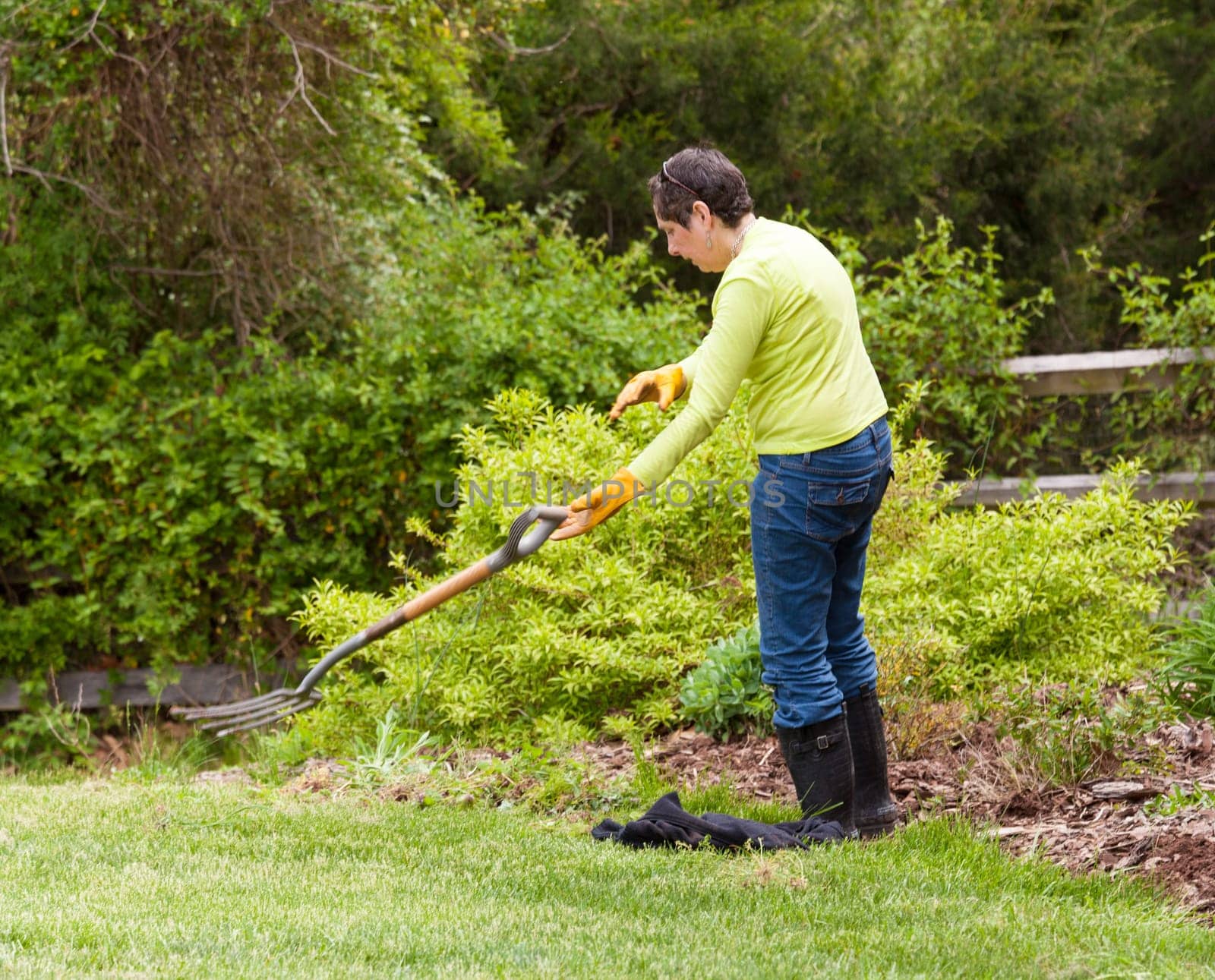 Woman gardener tosses away garden fork in frustration when weeding flowerbed
