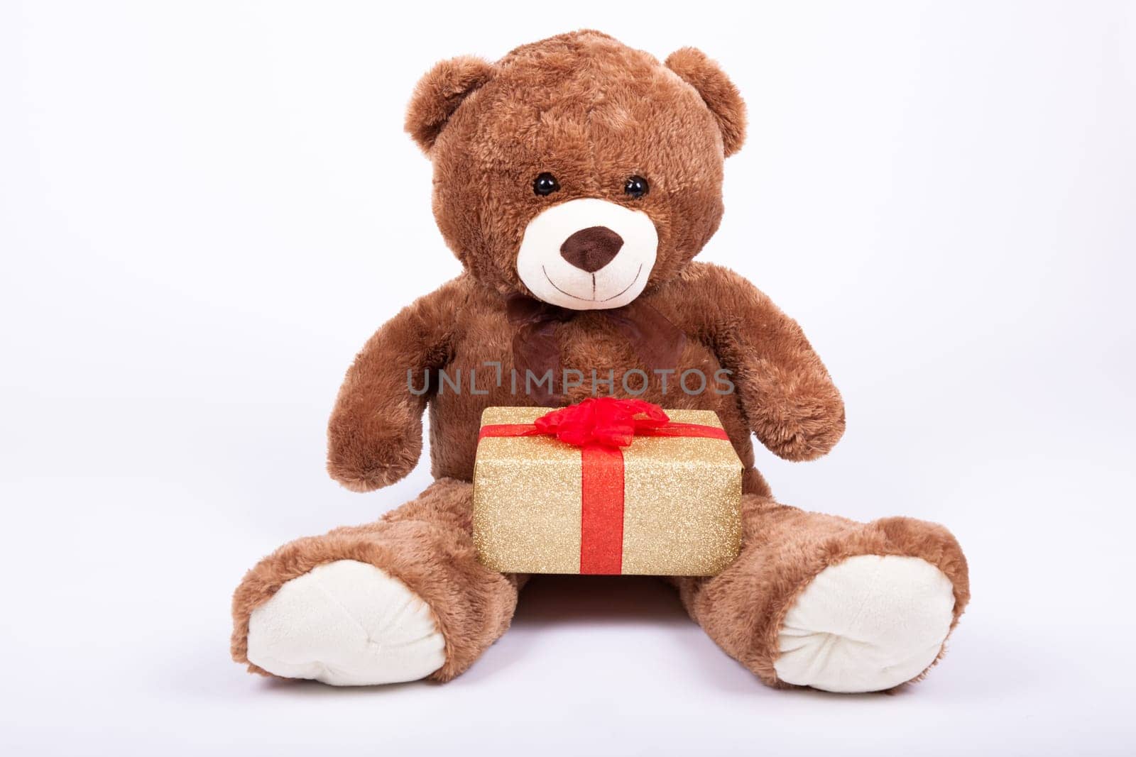 Seated teddy bear with gift boxes, over a white background
