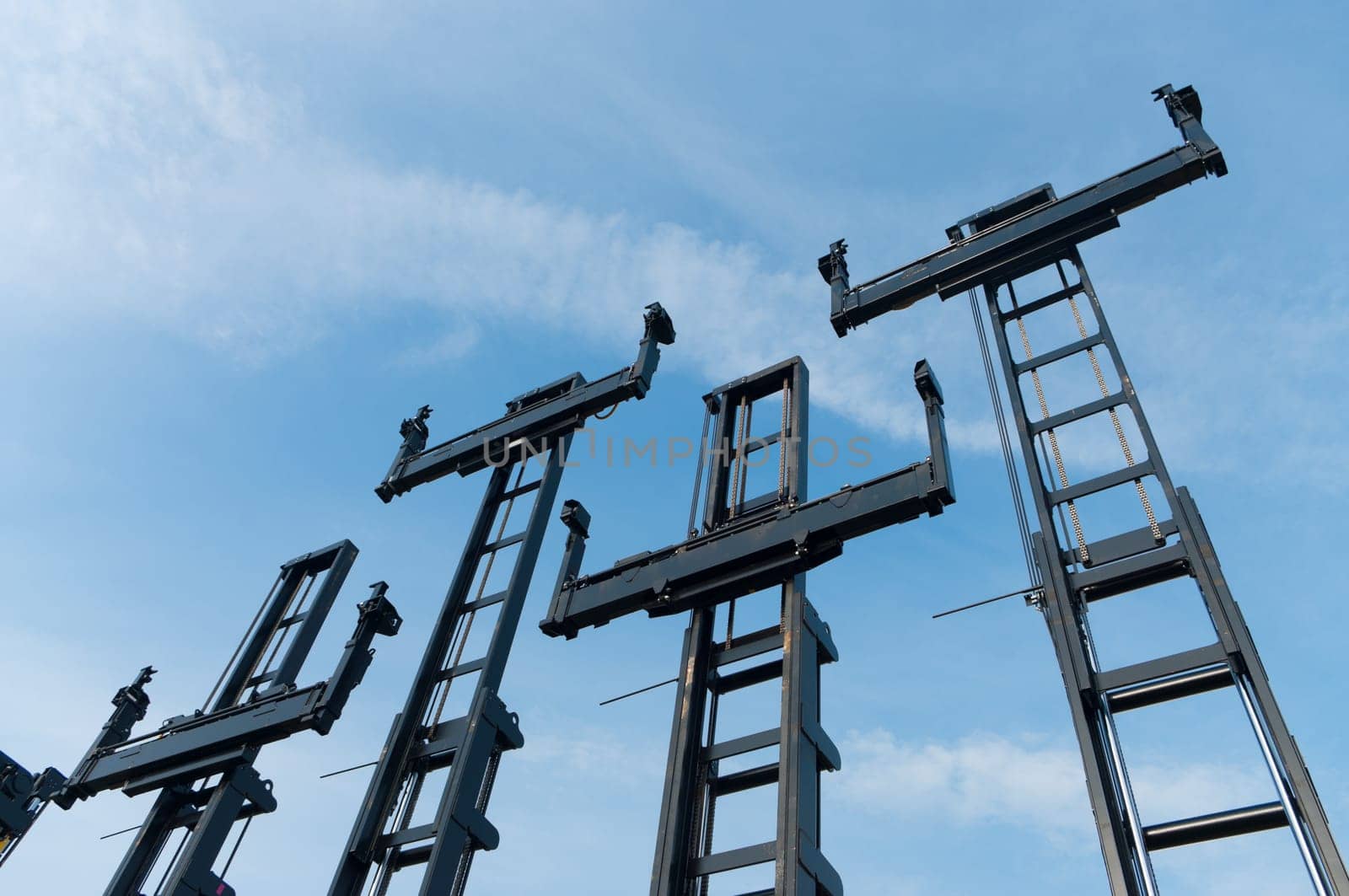 several forklifts for containers against a blue sky