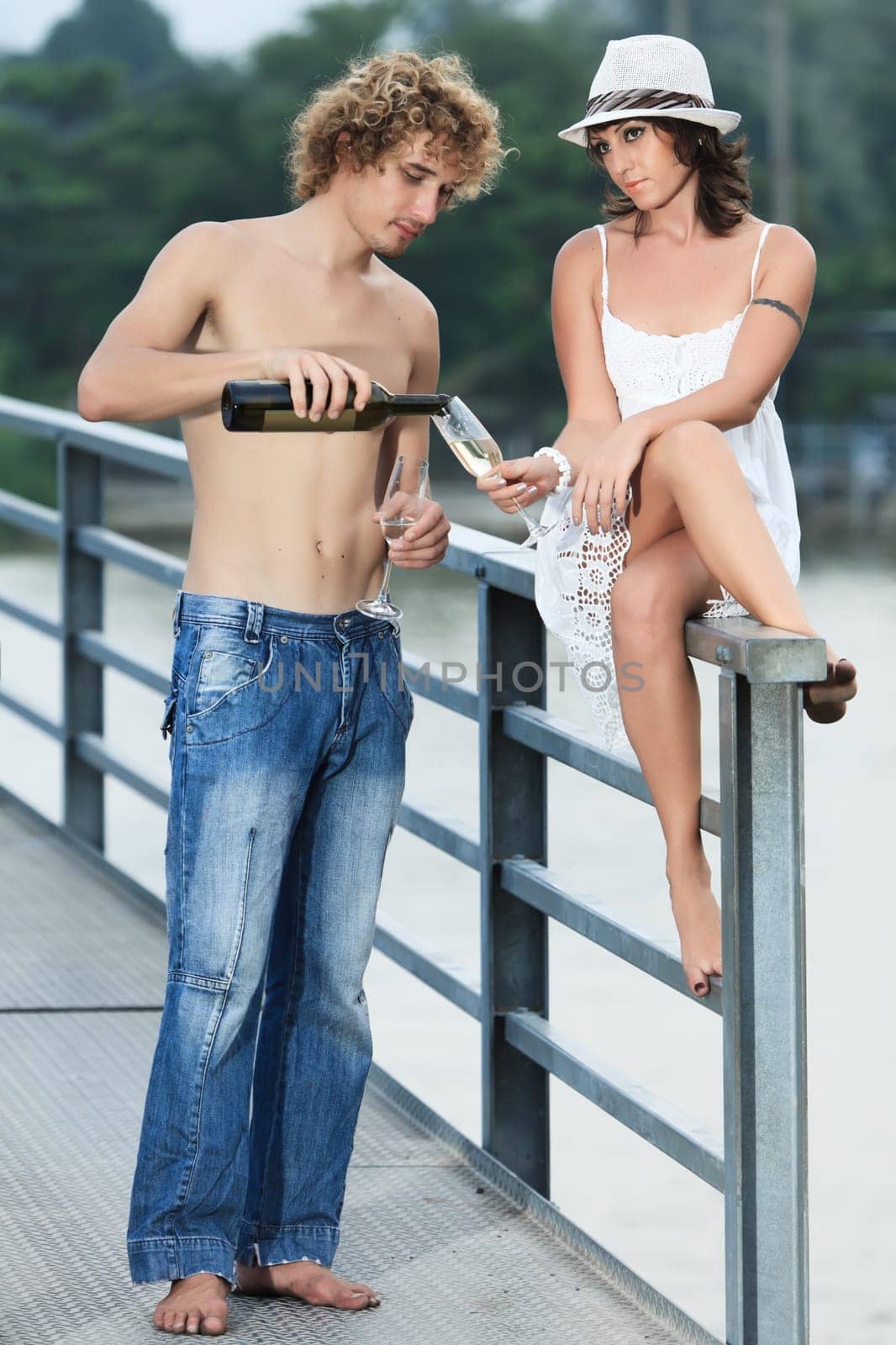Young couple drinking wine on a bridge