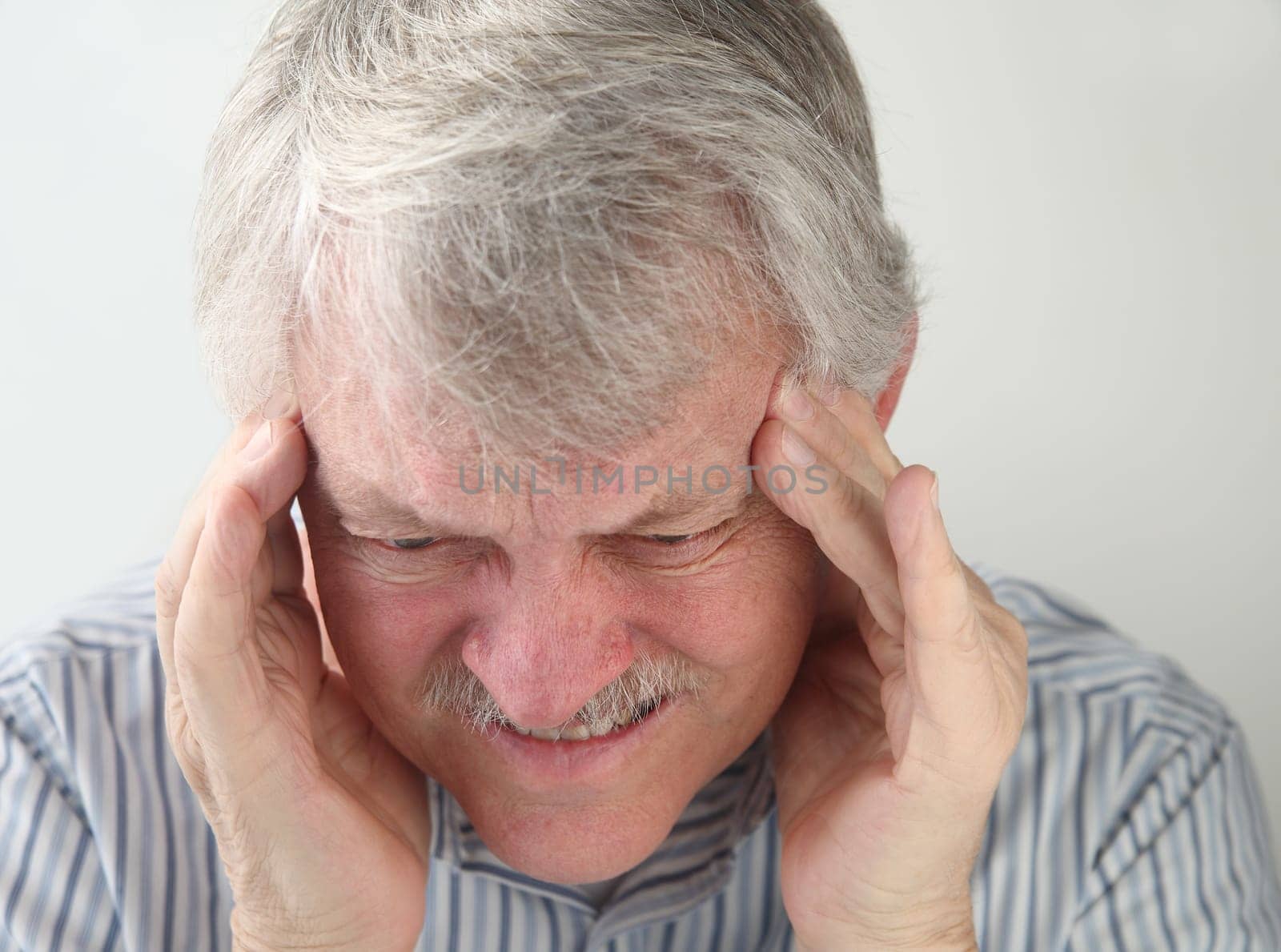 an older man suffers from a very bad headache