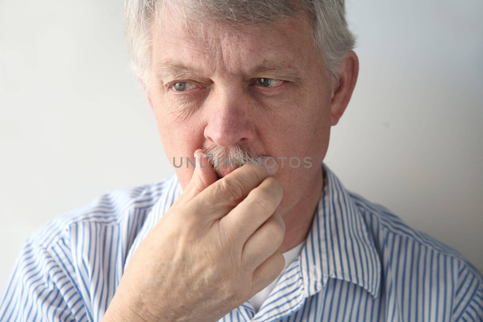an older man nervously tends to his facial hair