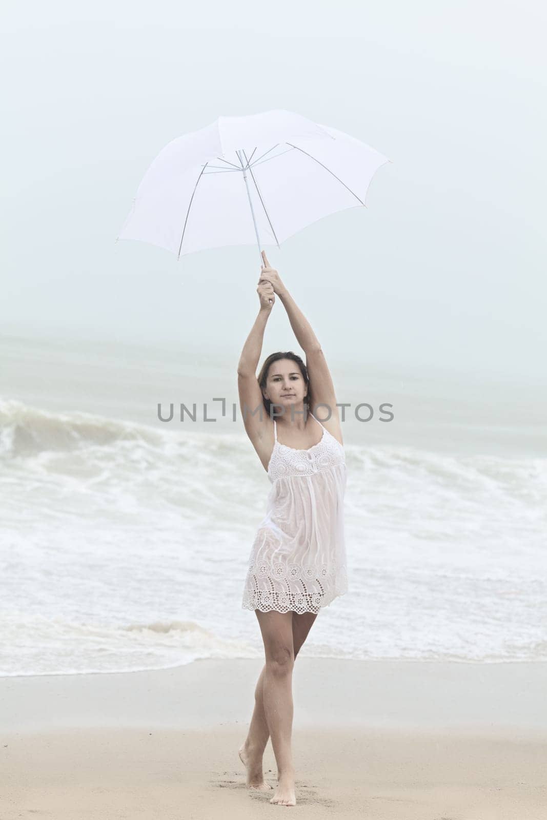 Beautiful woman near the stormy ocean at rain