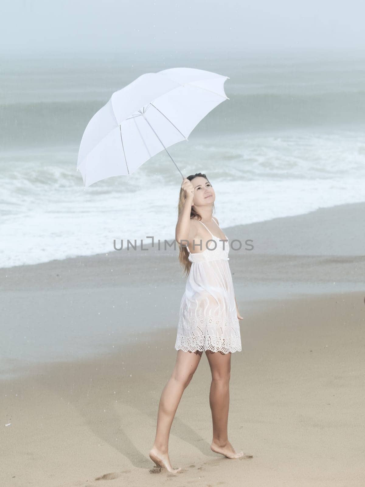 Beautiful woman near the stormy ocean at rain