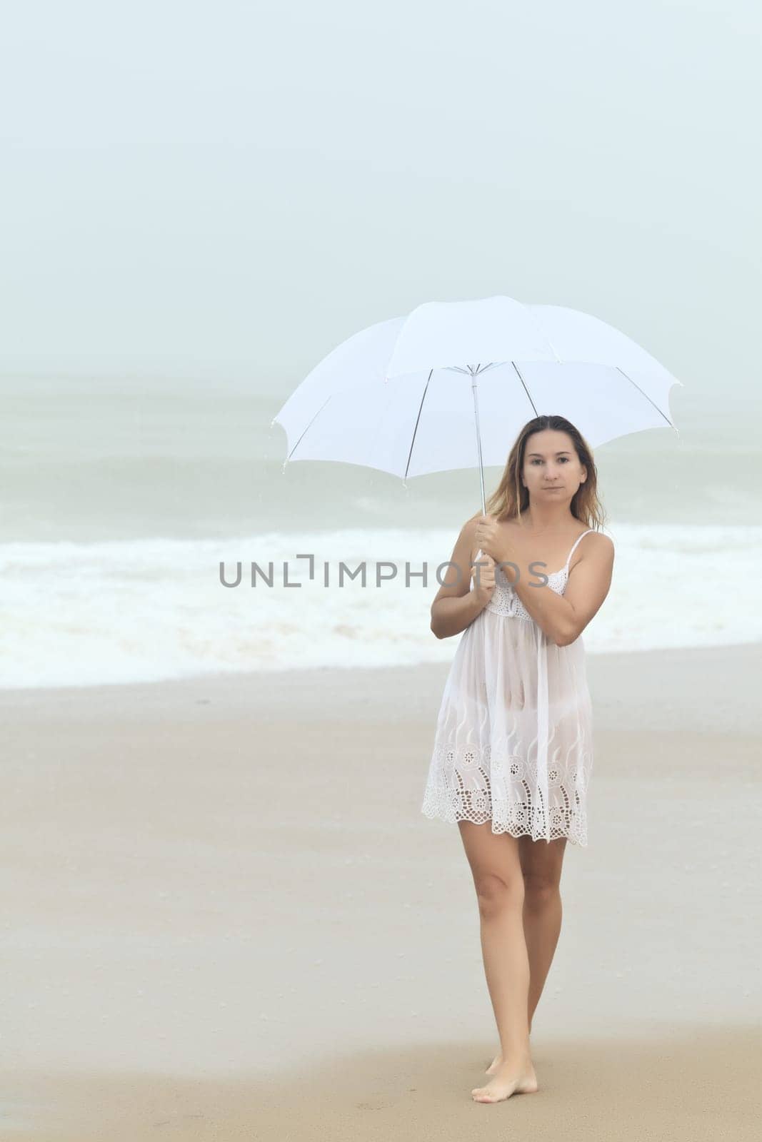 Beautiful woman near the stormy ocean at rain