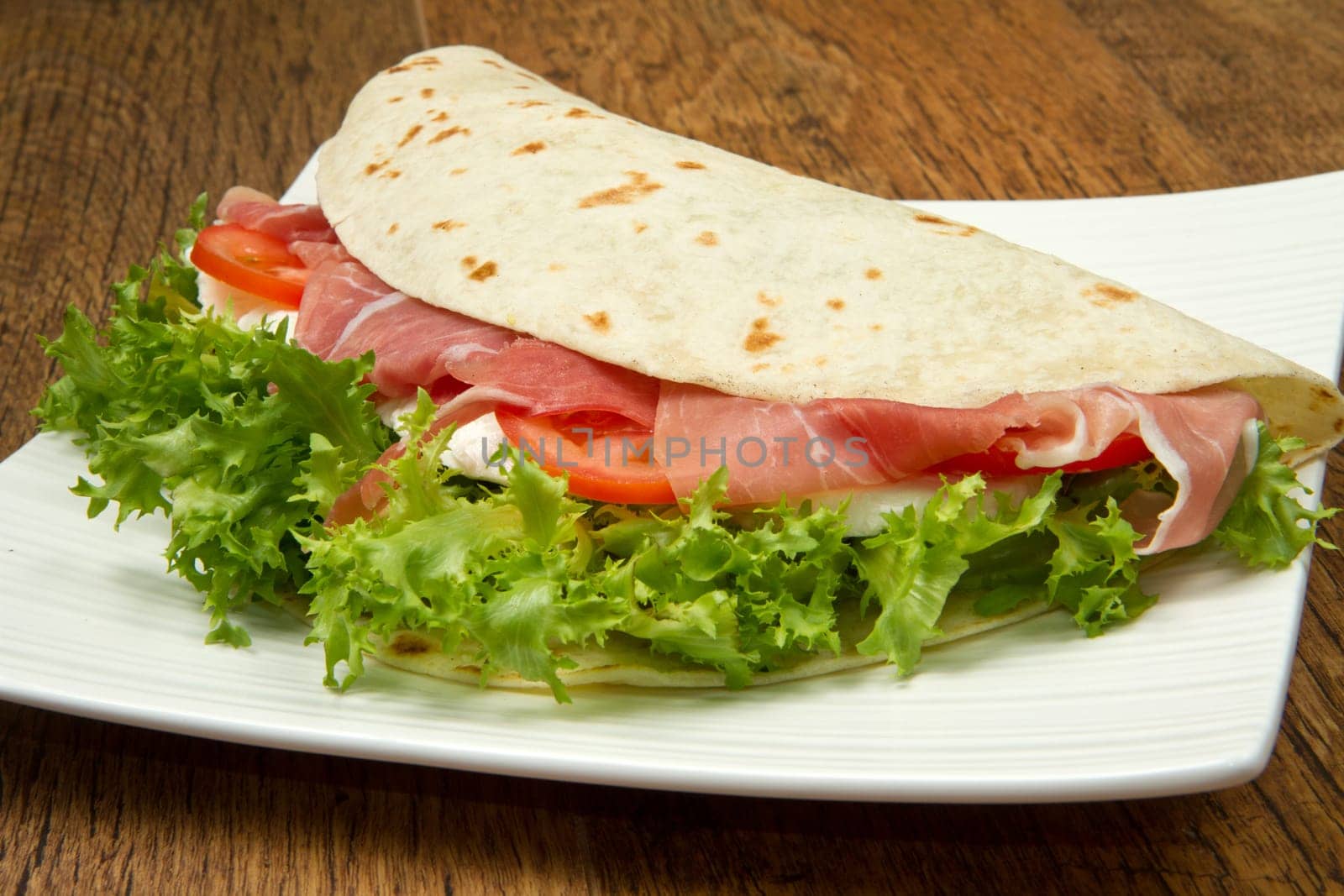 italian piadina with ham, fresh salad and mozzarella cheese