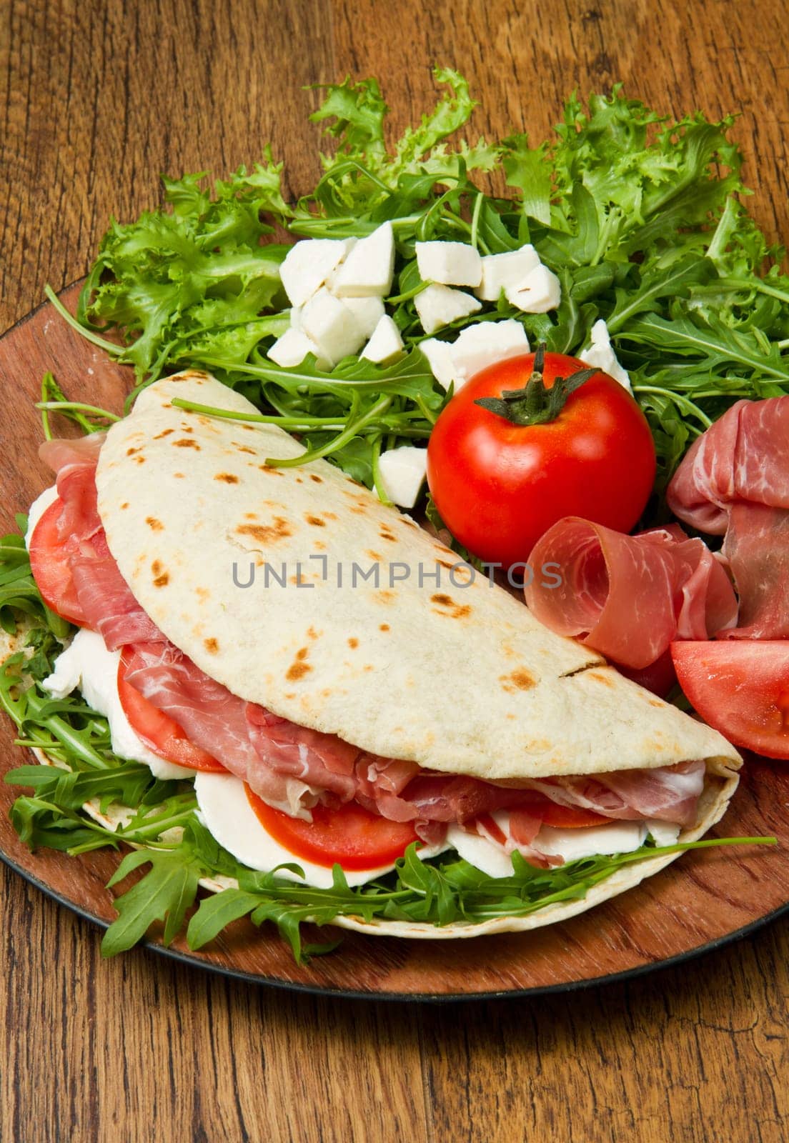 italian piadina with ham, fresh salad and mozzarella cheese