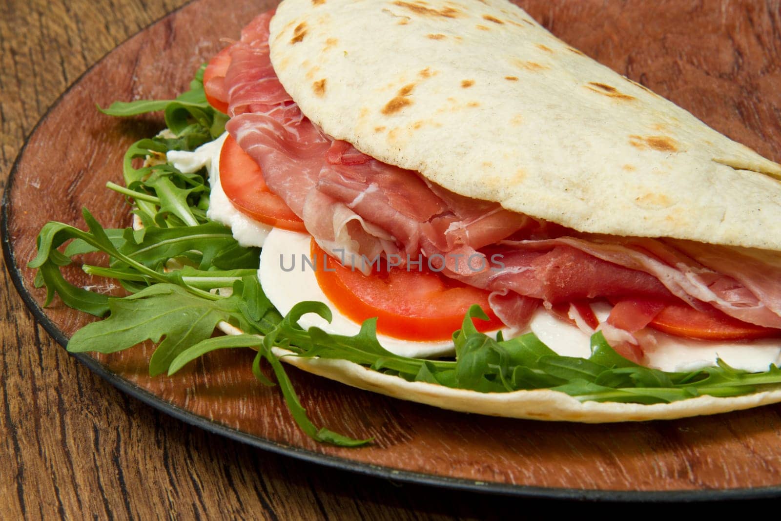 italian piadina with ham, fresh salad and mozzarella cheese