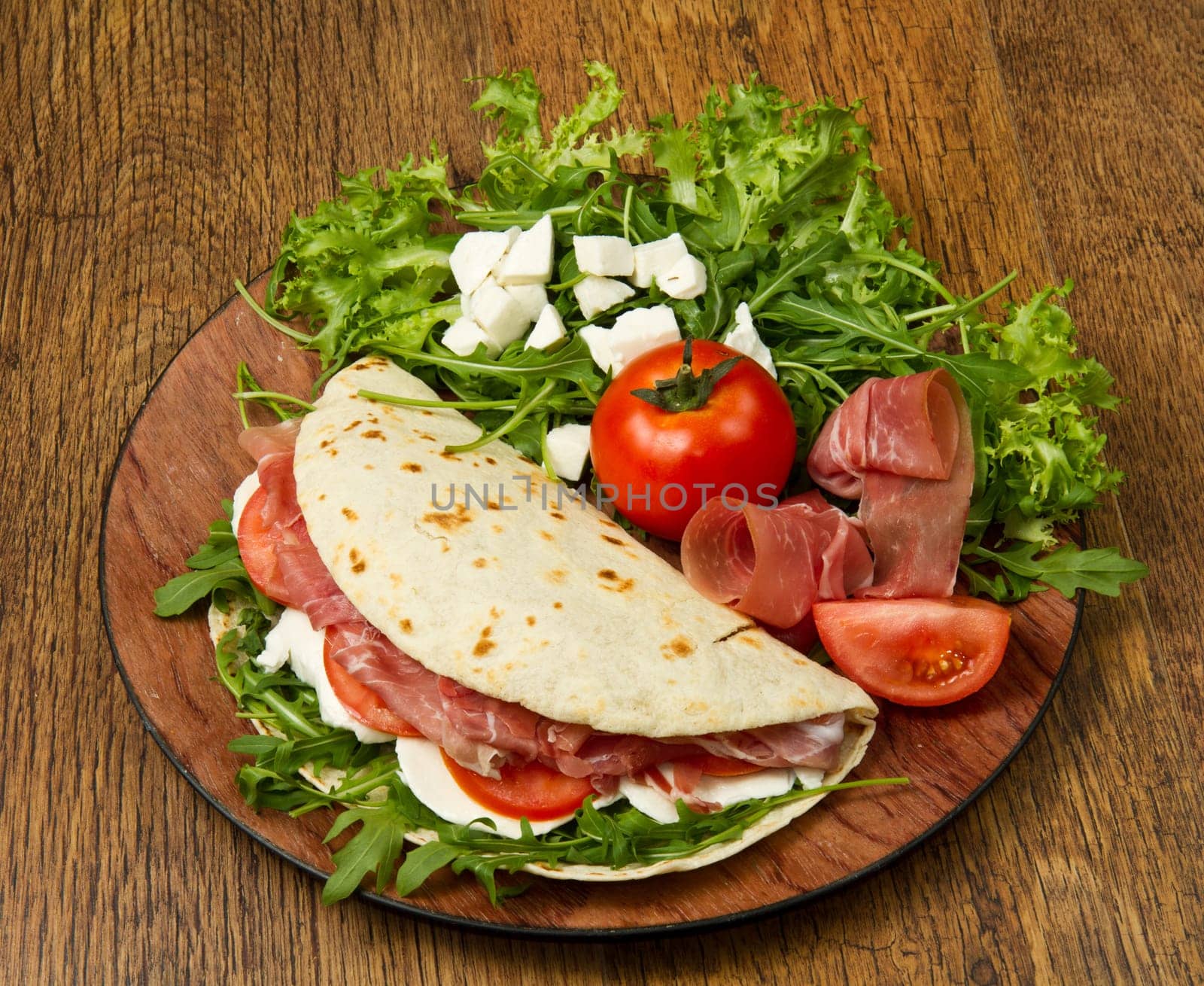italian piadina with ham, fresh salad and mozzarella cheese