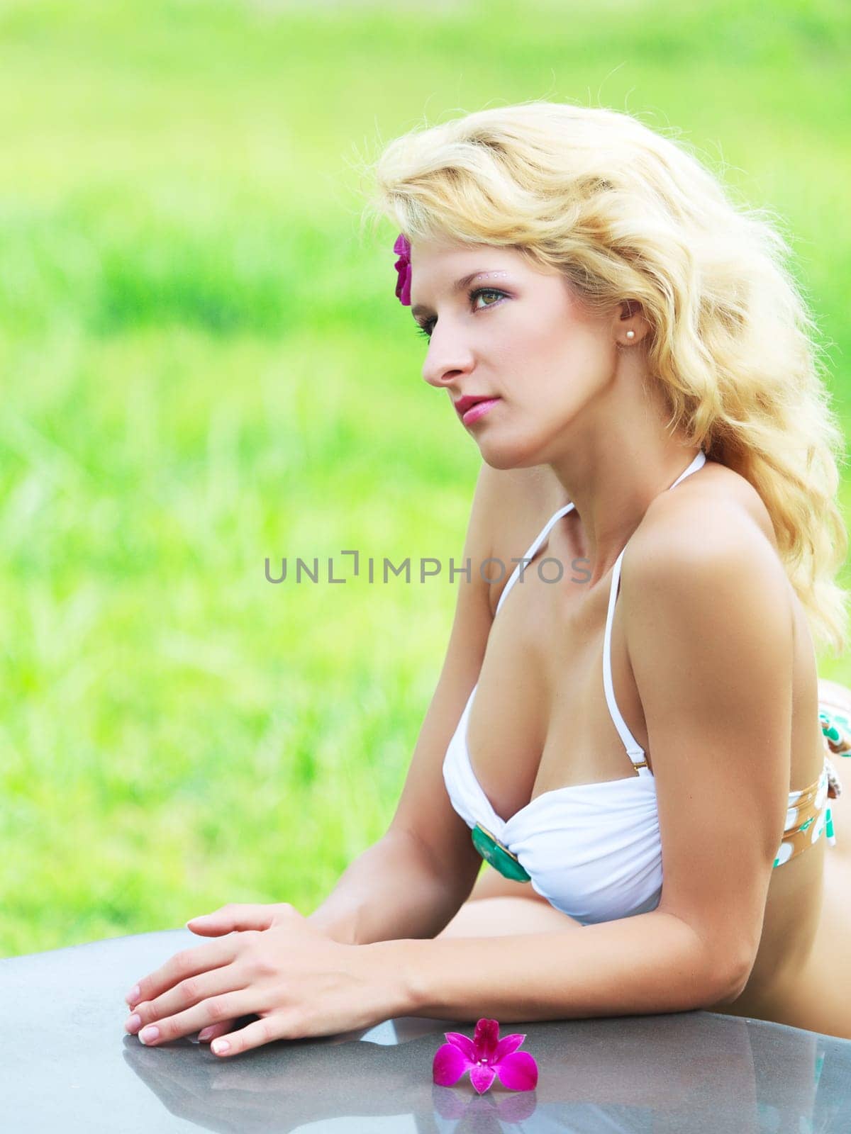 Beautiful woman in tropical garden leaning on the table