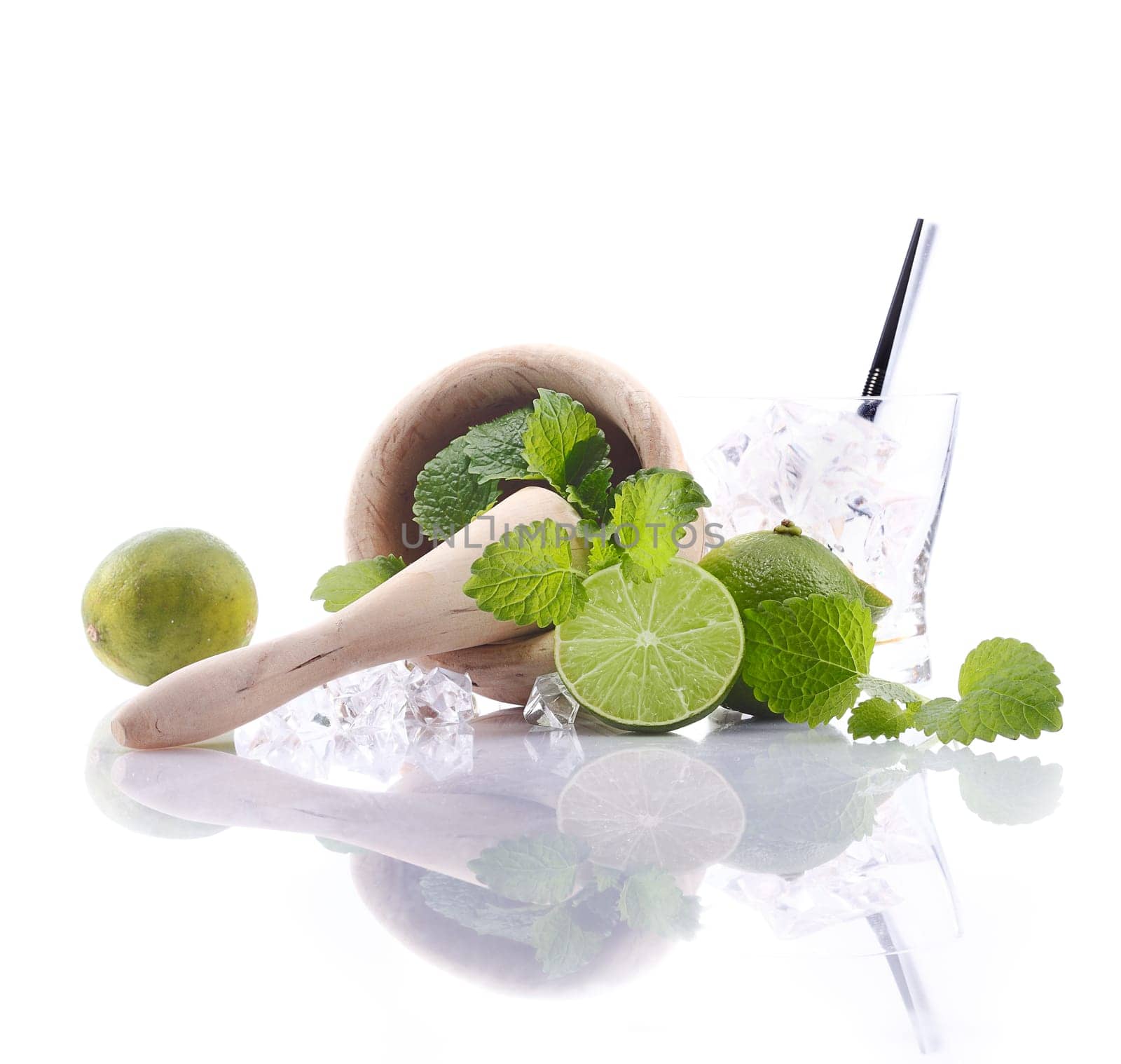 Caipirinha Ingredients with mortar and pestle and fresh lime. Aside an empty glass with ice cubes. For Drinkable Concepts