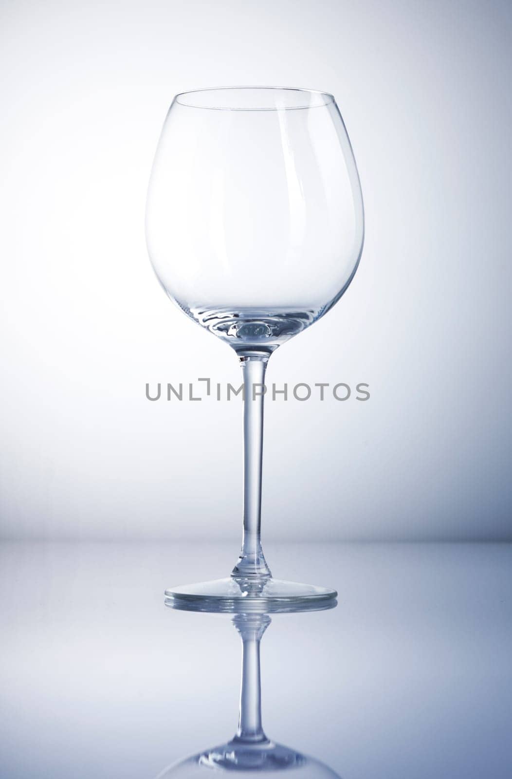 Empty wine glass with reflexion and a blue background