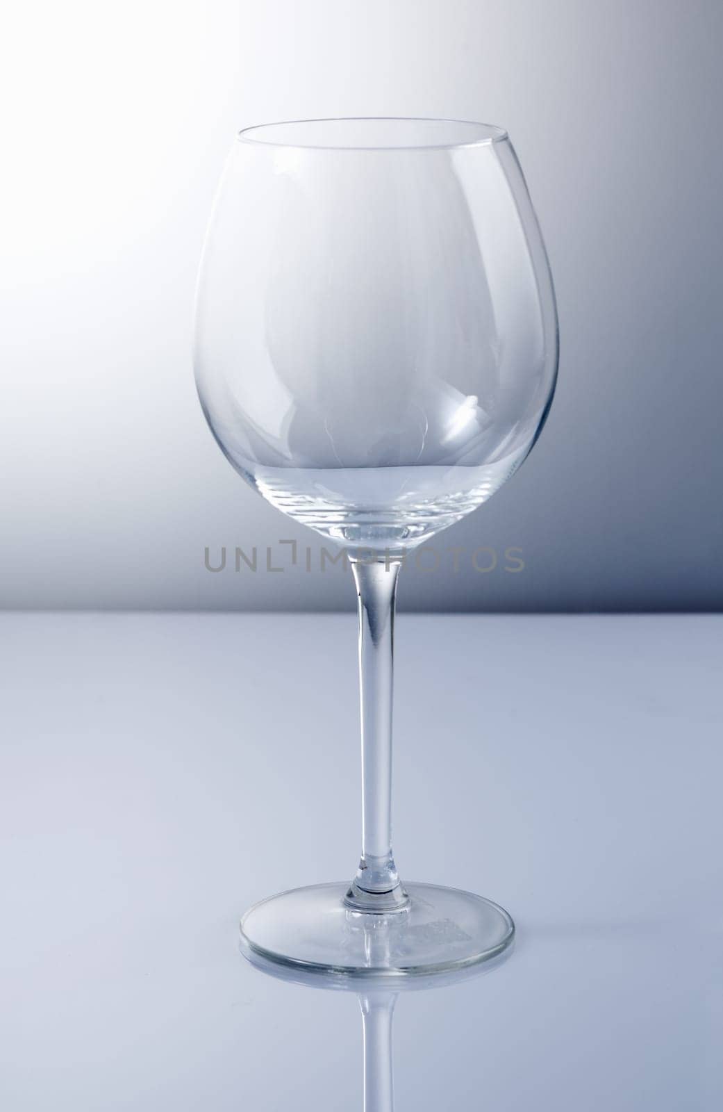 Empty wine glass with reflexion and a blue background