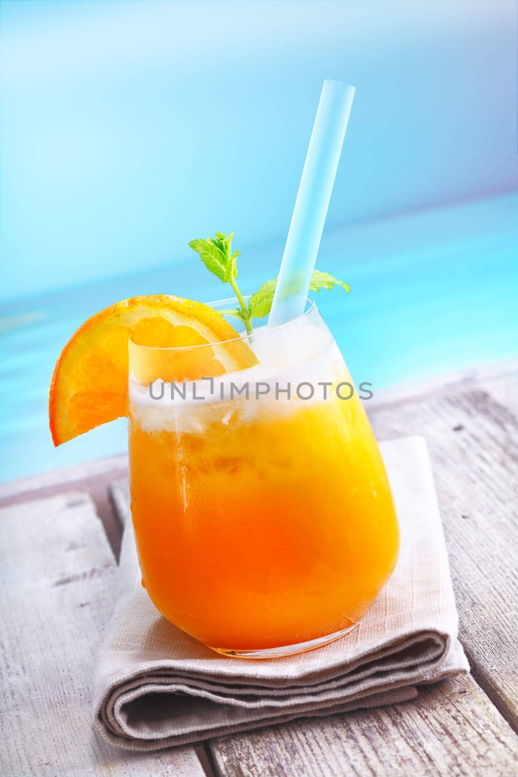 Refreshing iced orange cocktail standing on a wooden deck overlooking the ocean on vacation at a tropical resort