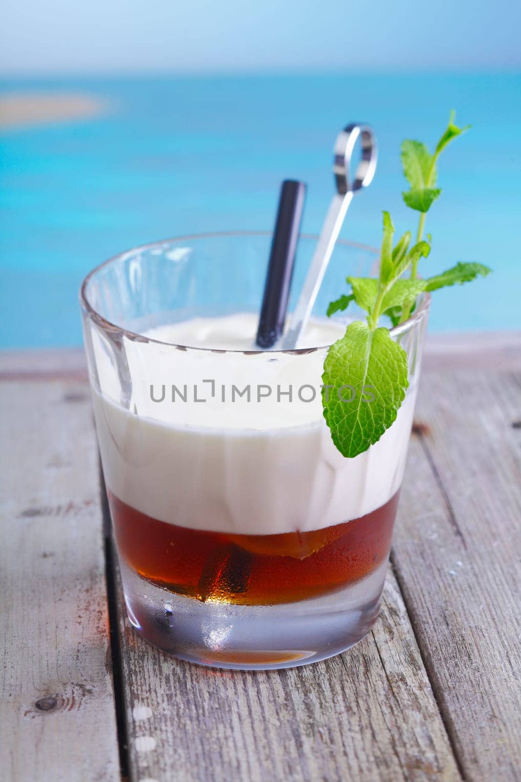 White Russian Coffee Cocktail with ice cubes and cream topping standing in a lounge at the beach, for alcoholic Drink Concepts. Visit my portfolio for more inspirations.