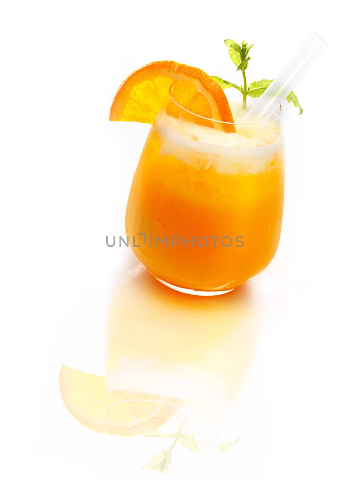 Glass of refreshing orange cocktail topped with ice on a reflective white surface