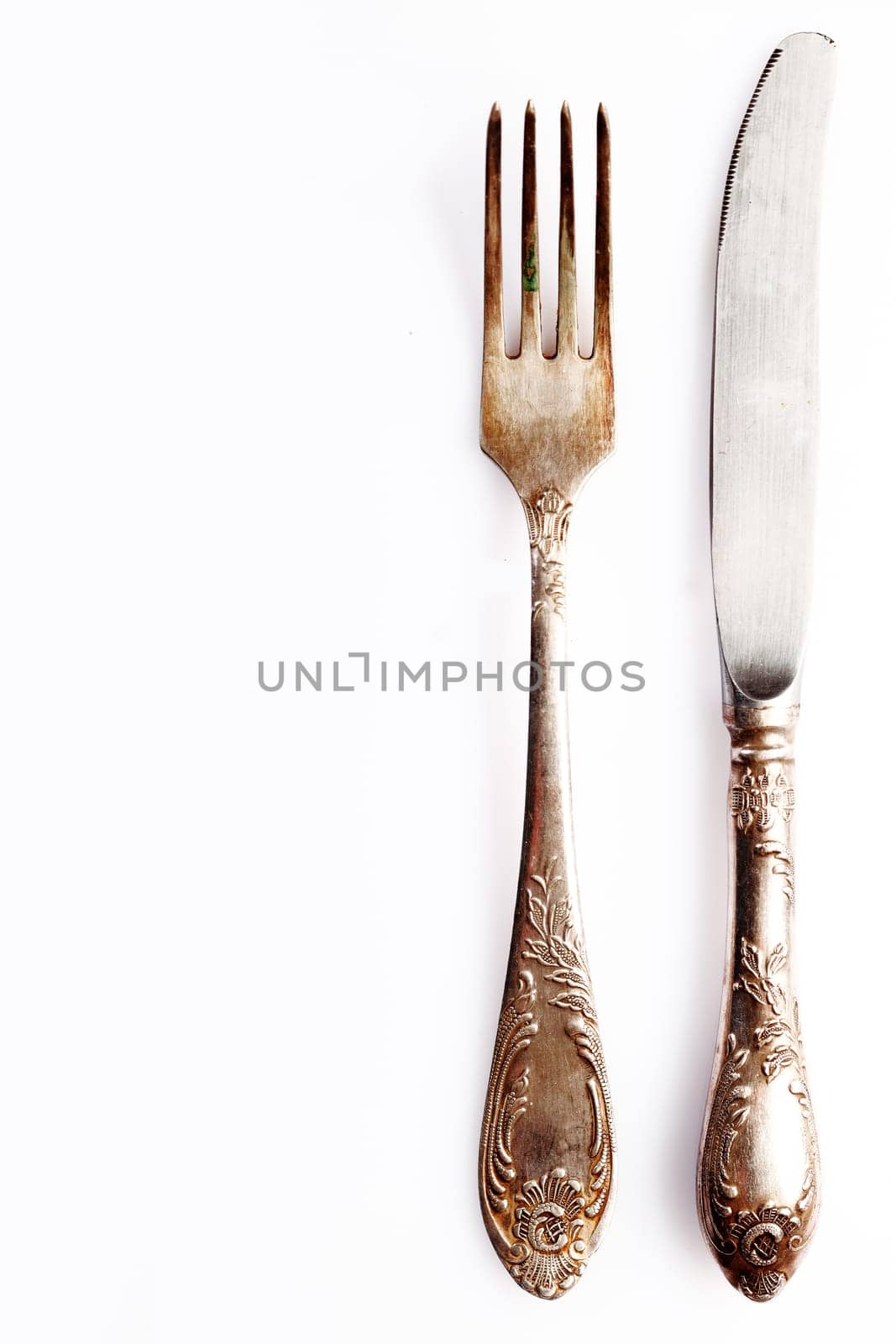 Silver cutlery setting comprising a knife anf fork on white with empty placement space for your food or text