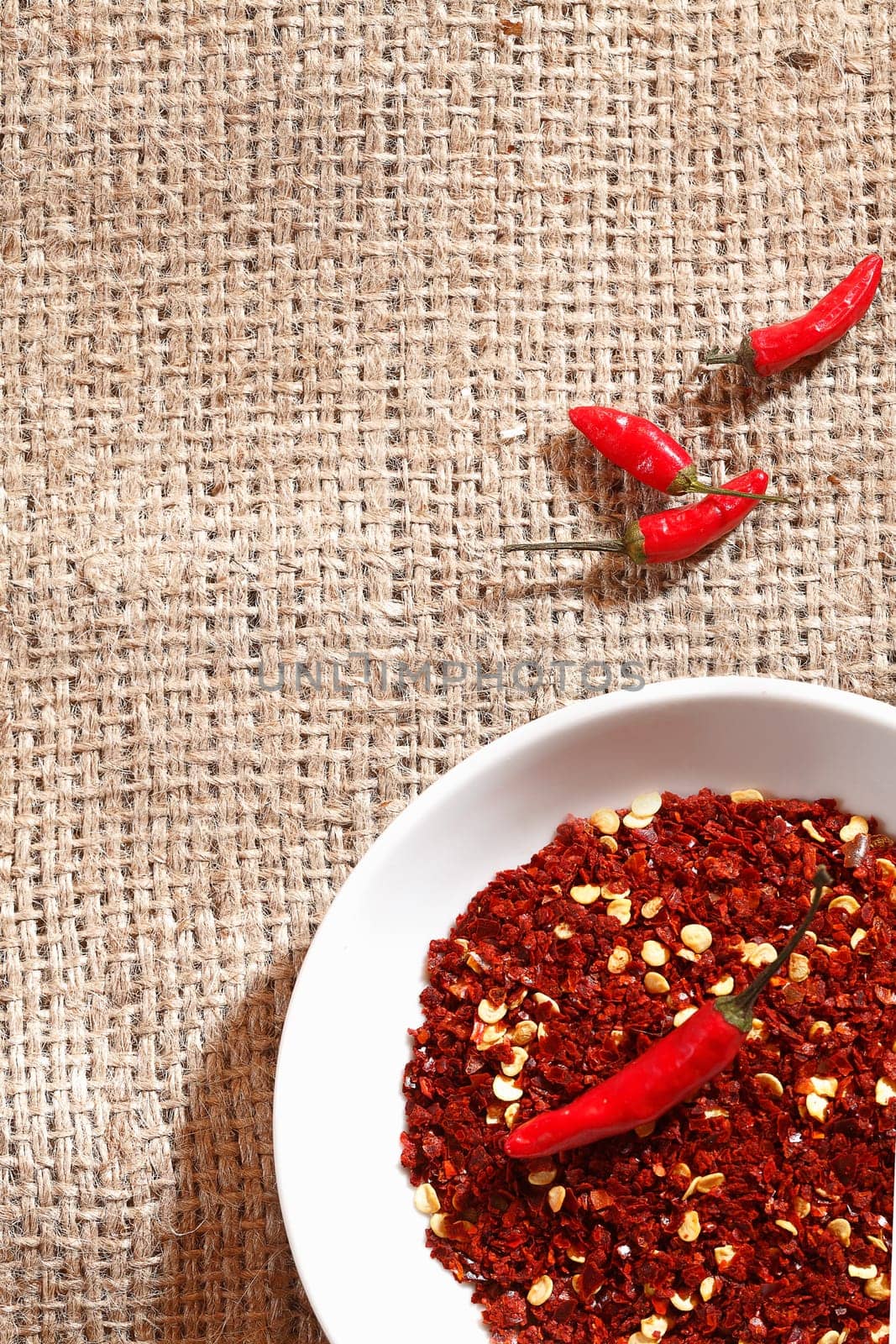 Dried and whole hot spicy red chilli peppers on hessian fabric ready for use as ingredients in cooking