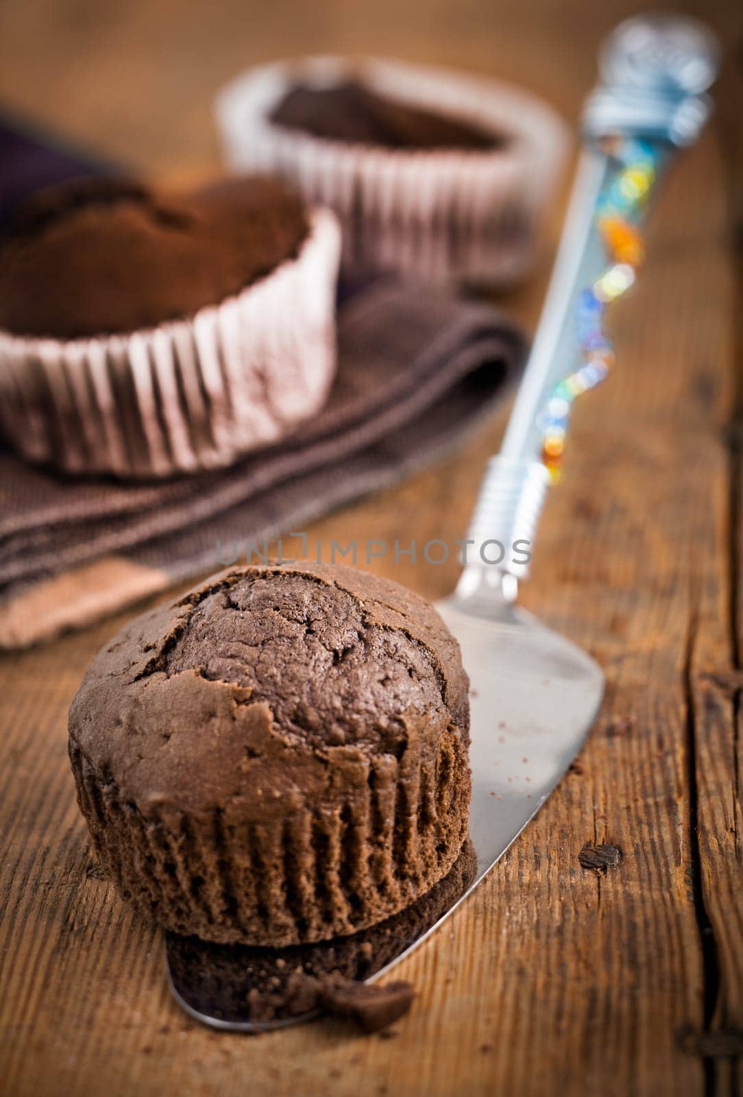 Serving a fresh healthy muffin on a metal spatula with a rustic wooden plank background