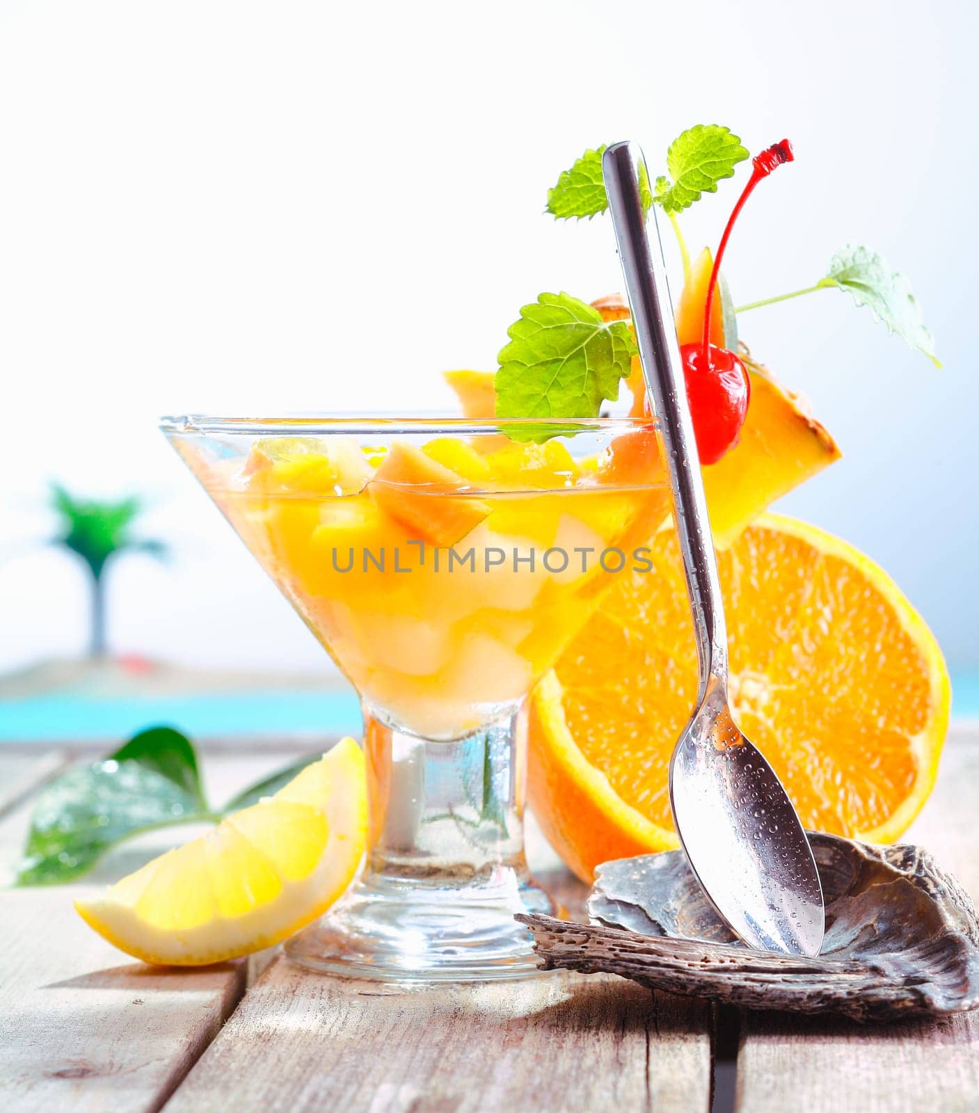 Colourful exotic fruit cocktail of fresh tropical fruits presented with a serving spoon in a rest at an upmarket resort