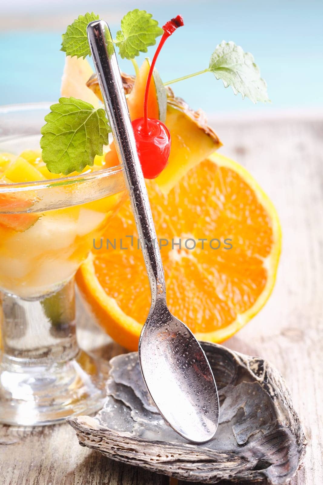 Serving spoon on a shell rest accompanying a glass of tropical fruit cocktail at an upmarket catering establishment
