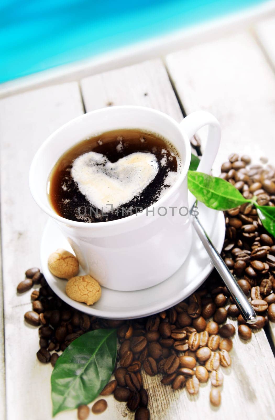 Coffee in a Cafe near the beach with a heart of cream and coffee beans around. Standing on a Table at a Coffee Bar at the coastline near the beach for your Travel cuisine concepts.