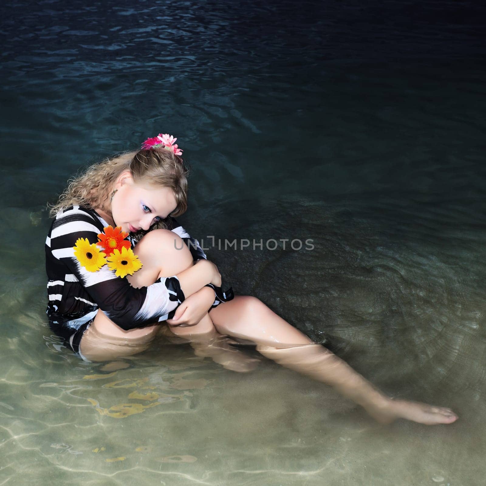 Beautiful woman with flowers in the sea