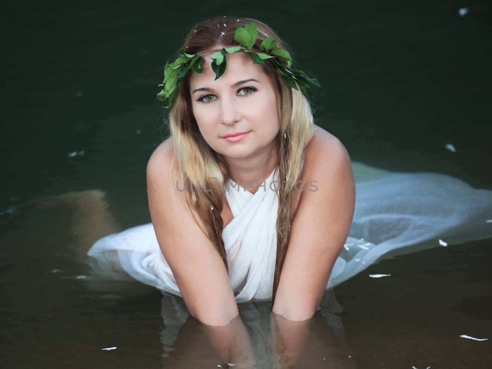 Beautiful woman as a forest nymph on the river