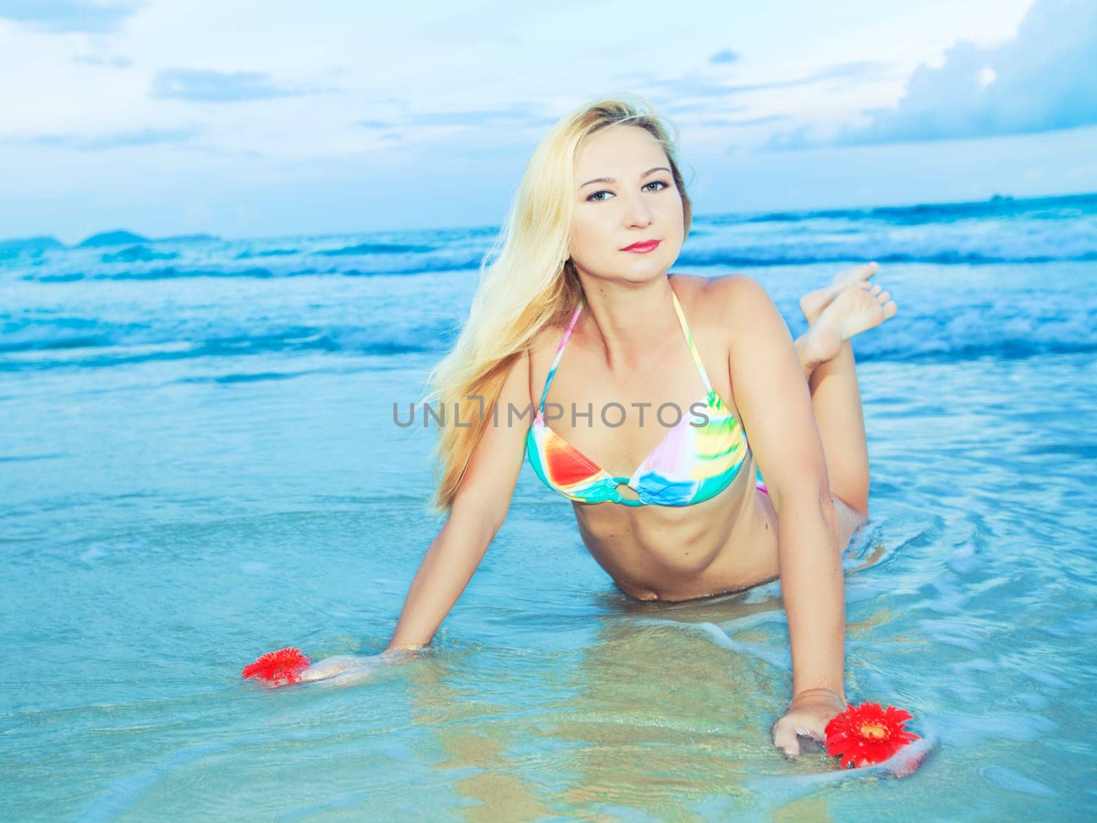 Beautiful young woman with flower at the beach