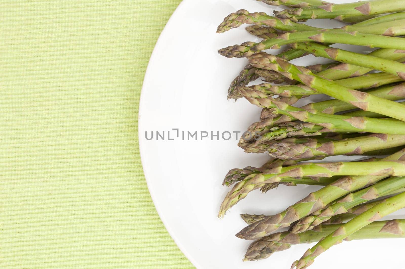 Spears of Fresh Uncooked Asparagus on White Plate