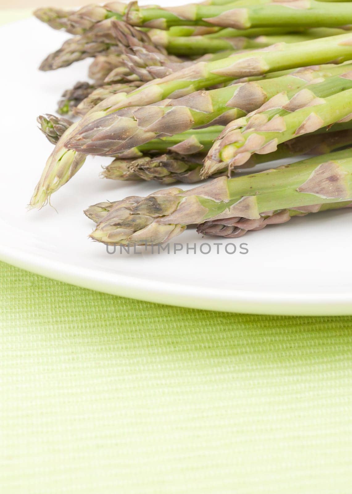 Spears of Fresh Uncooked Asparagus on White Plate - Shallow Depth of Field