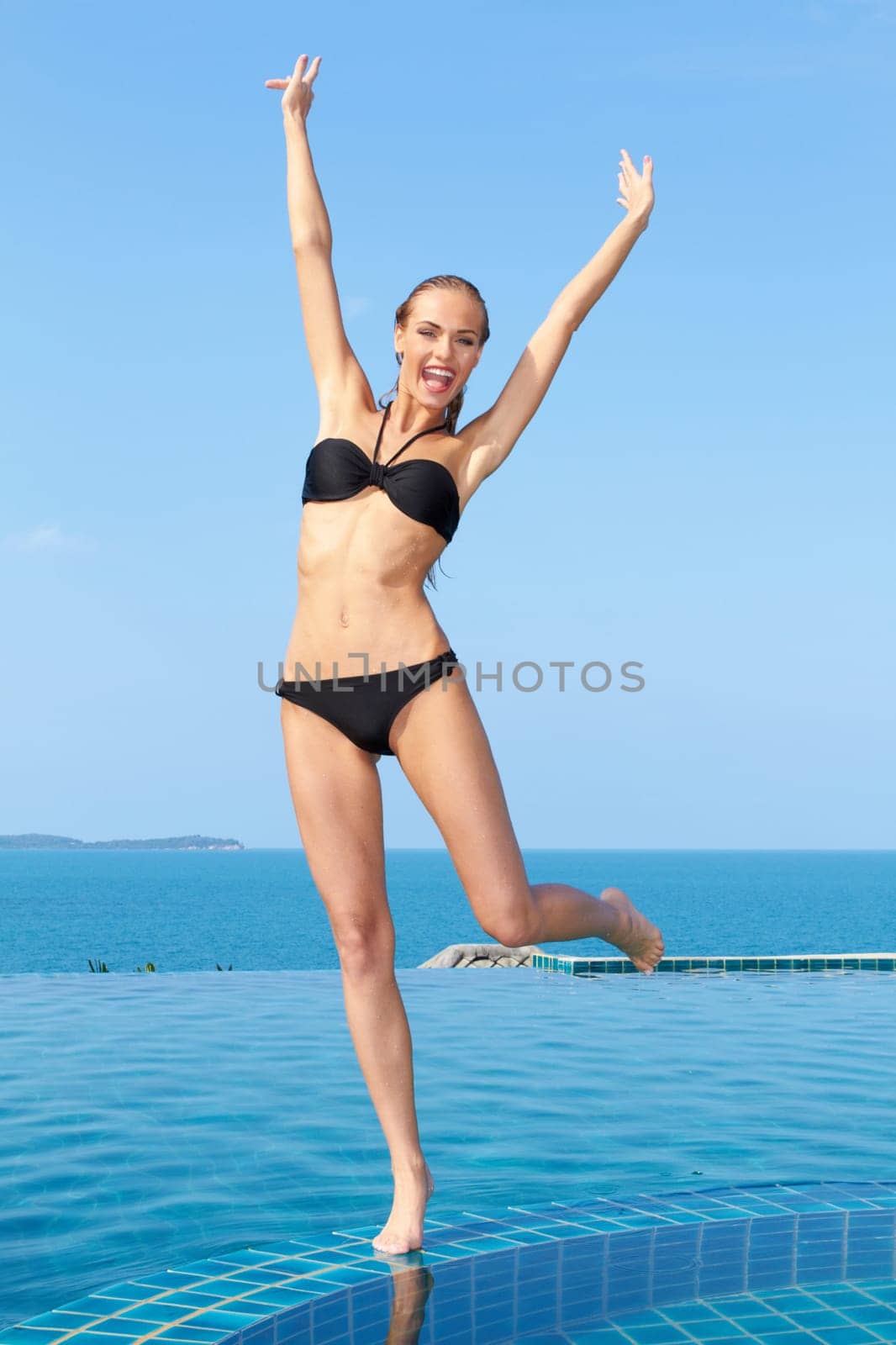 Portrait of carefree woman having fun with arms outstretched at the pool