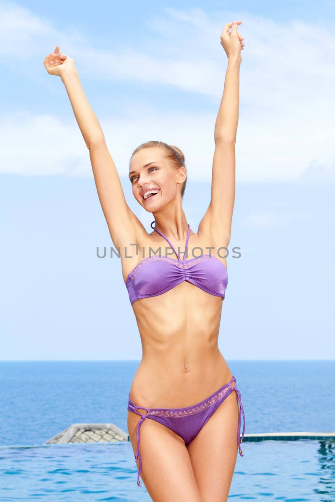 Portrait of carefree woman having fun with arms outstretched at the pool