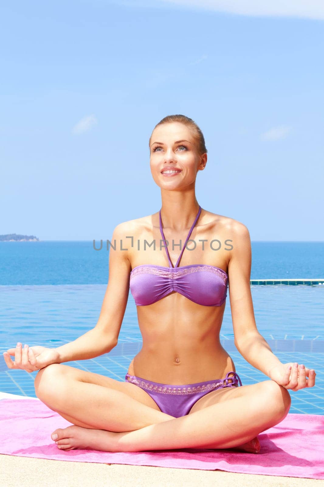 Beautiful woman sitting in yoga position at the edge of pool