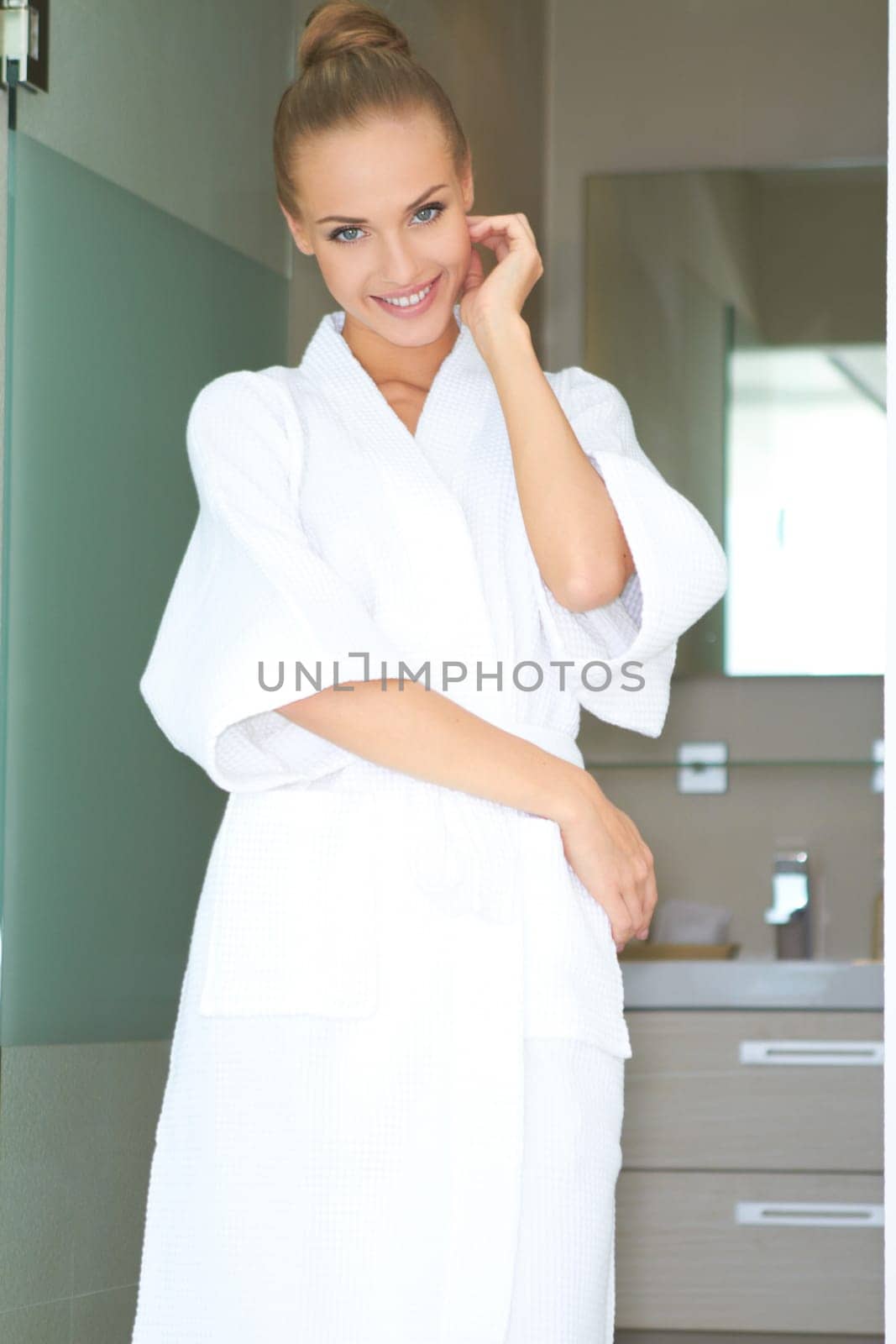 Relaxed woman standing in white bathrobe in modern room