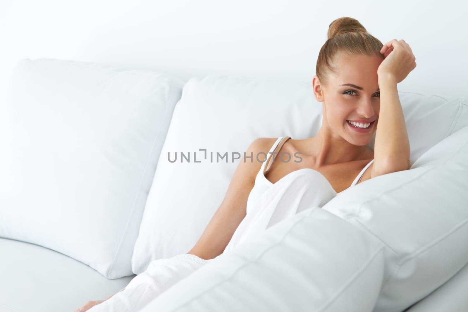 Happy young woman sitting on couch in her home