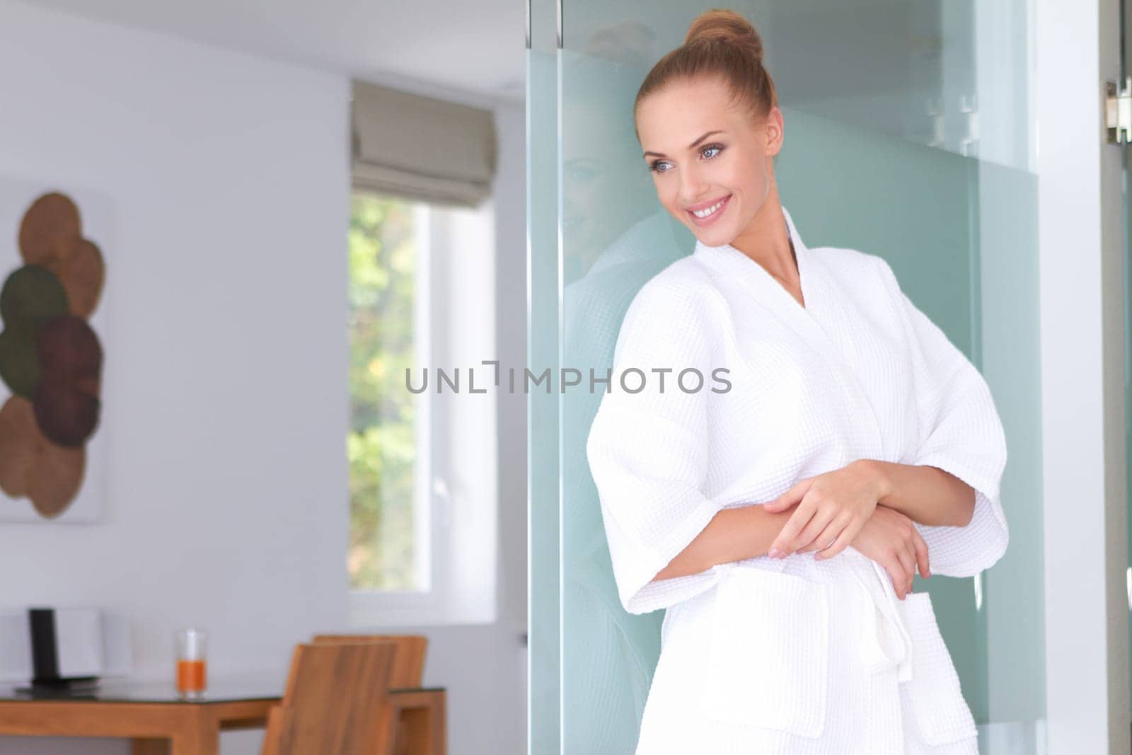 Beautiful woman standing in white bathrobe in modern room