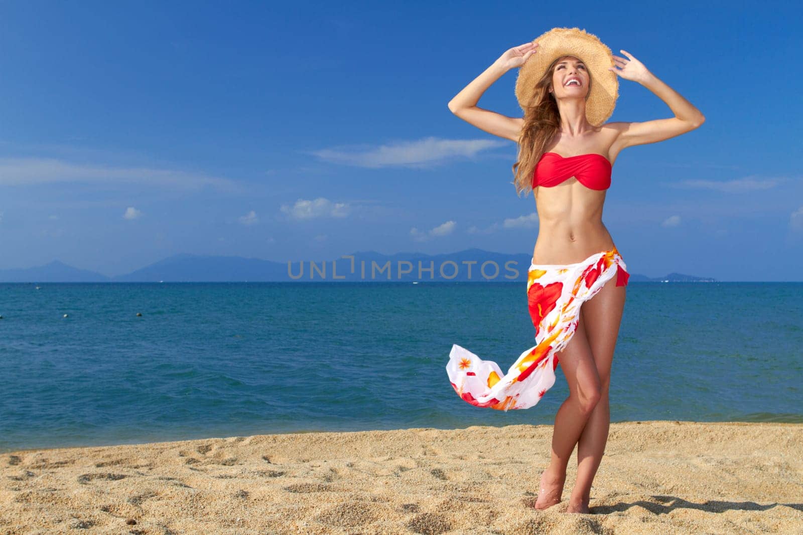 Girl wearing bikini and hat and posing at the sandy beach