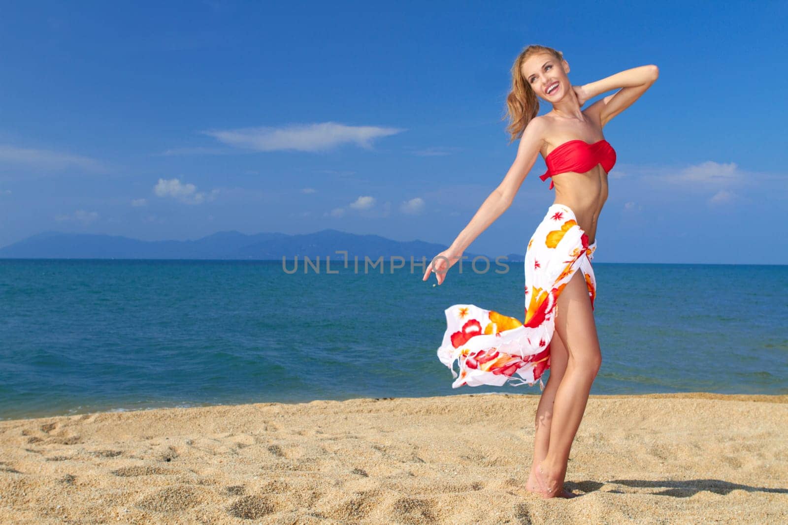 Pretty blonde girl wearing a bikini in a happy mood at the beach